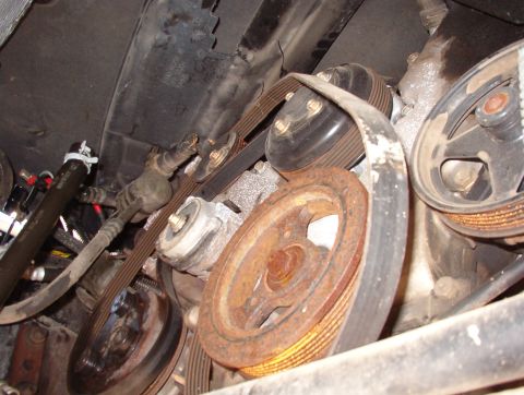 1994 Ford Crown Victoria - Close-up view of the engine bay, showing various belts and pulleys, some showing signs of rust.
