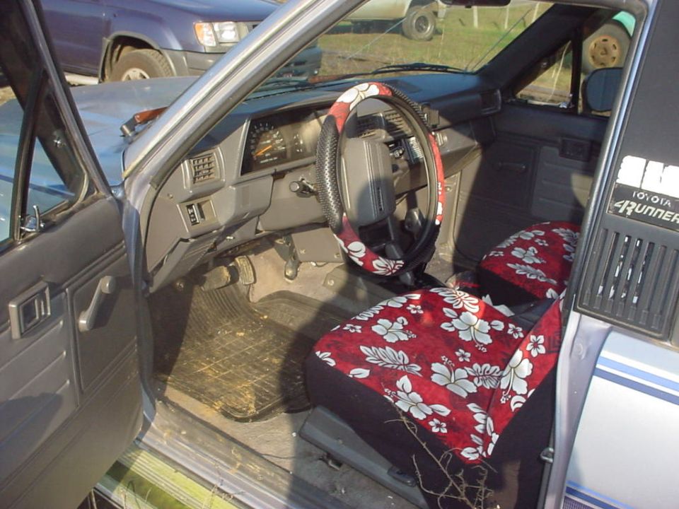 Truck interior with red hibiscus-print Hawaiian seat covers and matching steering wheel cover, Toyota 4Runner panel visible