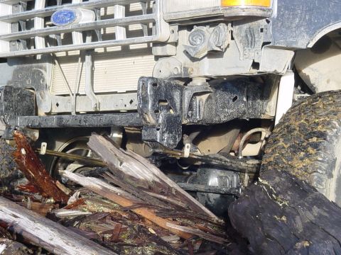 1987 Ford Bronco - The front of a Ford truck is shown, partially obscured by debris and wood.