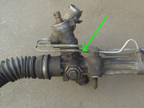 1993 Ford Taurus - Close-up of a power steering rack and pinion assembly, with a green arrow indicating a specific fluid line.