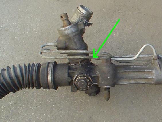 Power steering rack and pinion assembly with green arrow pointing to fluid line
