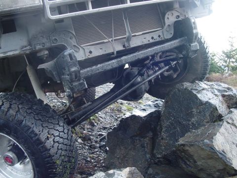 1987 Ford Bronco - This off-road vehicle navigates a rocky terrain, showing its front suspension and grille.