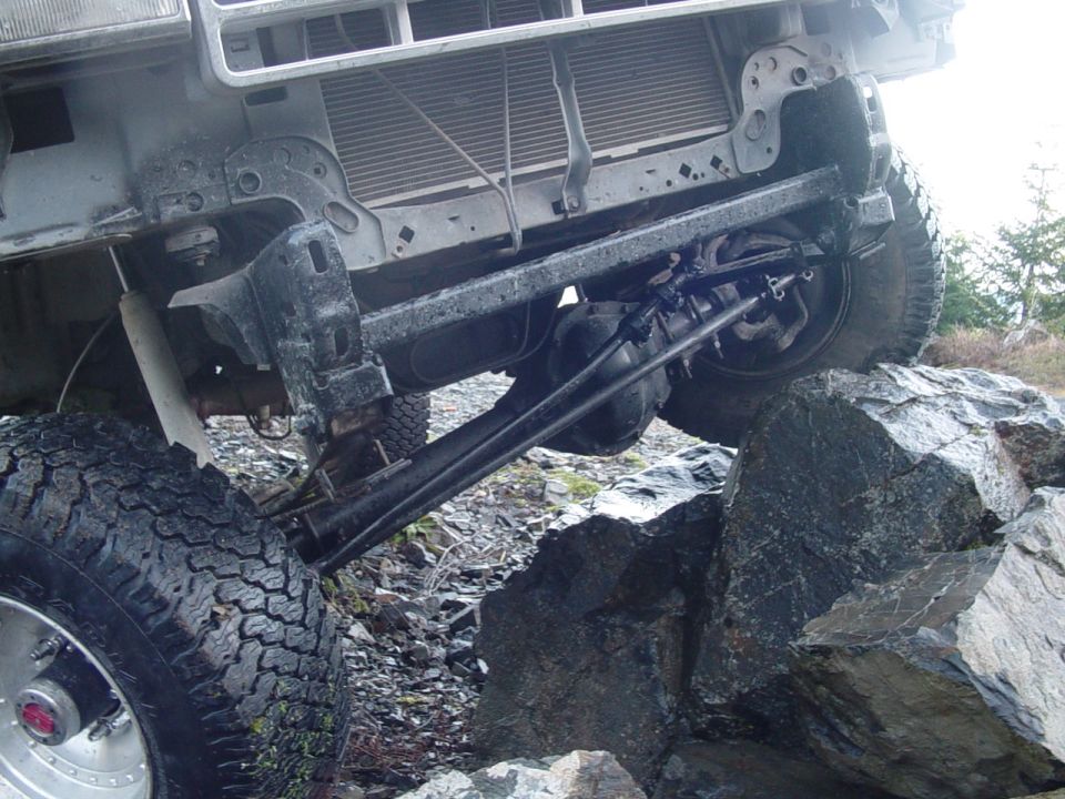 Off-road vehicle with front suspension and grille visible, on rocks
