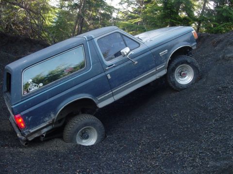 1987 Ford Bronco - A blue 1987 Ford Bronco navigates a steep, loose dirt incline.