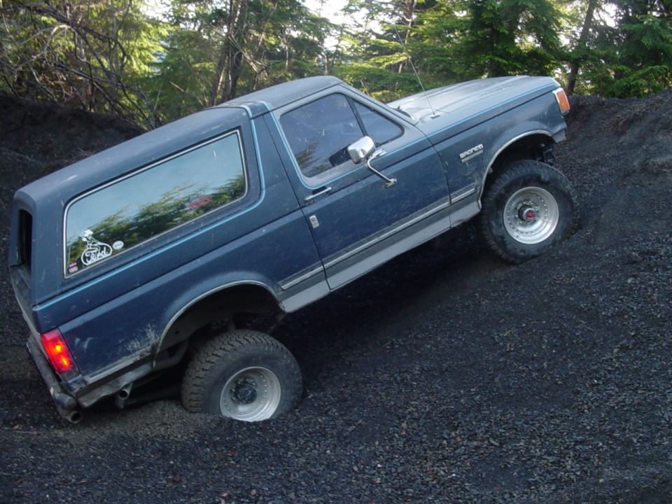 Blue 1987 Ford Bronco climbing a dirt hill