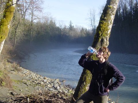 1987 Ford Bronco - A person pauses to drink water while enjoying a view of a misty river and wooded area.