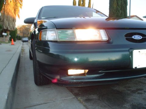 1993 Ford Taurus - Front view of a dark green 1992 Ford Taurus parked on a residential street with its headlights illuminated.
