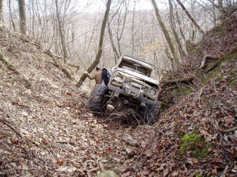 1992 Ford Bronco - Off-road vehicle navigating a challenging, wooded ravine with steep inclines.