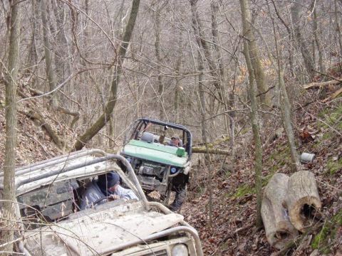 1992 Ford Bronco - Two off-road vehicles are shown navigating a challenging wooded trail, with one vehicle appearing to be stuck.