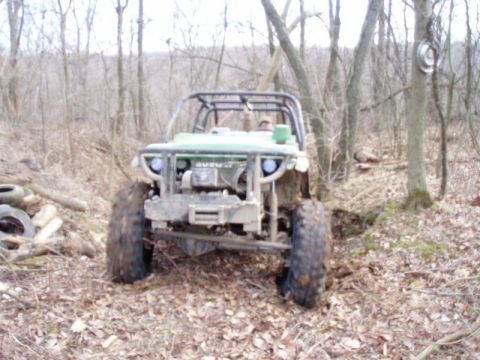 1992 Ford Bronco - This modified off-road vehicle is parked in a forest clearing surrounded by trees and fallen leaves.