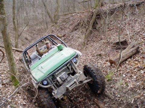 1992 Ford Bronco - Off-road buggy navigates a challenging wooded incline.