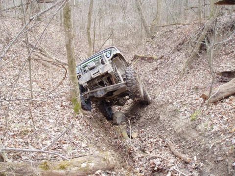 1992 Ford Bronco - This vehicle is navigating a challenging off-road trail through a dense forest.