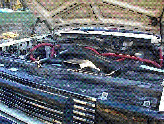 Open engine bay under hood showing radiator support and red battery cables