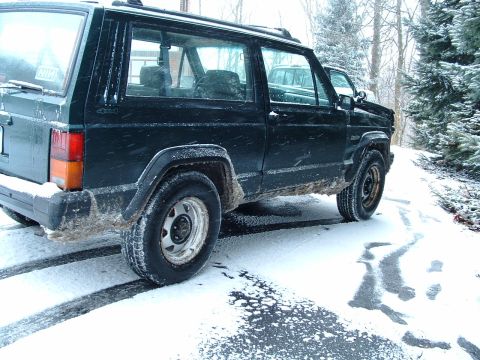 1994 Volkswagen Jetta - A dark green Jeep Cherokee XJ is parked on a snow-covered road, with another vehicle visible behind it.