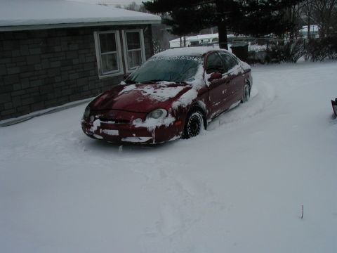 1997 Ford Taurus - A red 1997 Ford Taurus is stuck in deep snow next to a brick house.