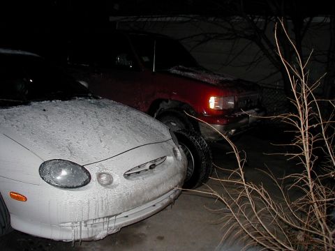 1997 Ford Taurus - Two vehicles covered in snow and ice at night.