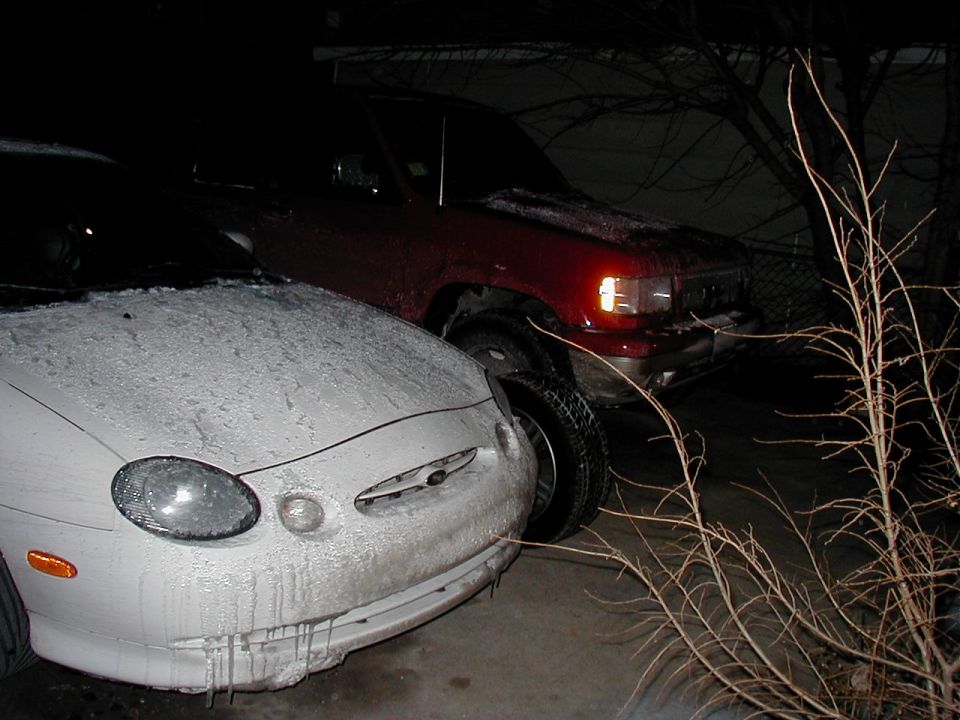 1997 Ford Taurus front end covered in snow and ice, parked next to a red SUV