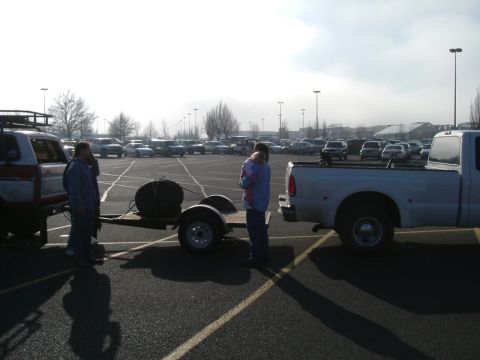 1993 Ford Bronco - A white pickup truck is seen from the rear, towing a small trailer that carries a spare tire.