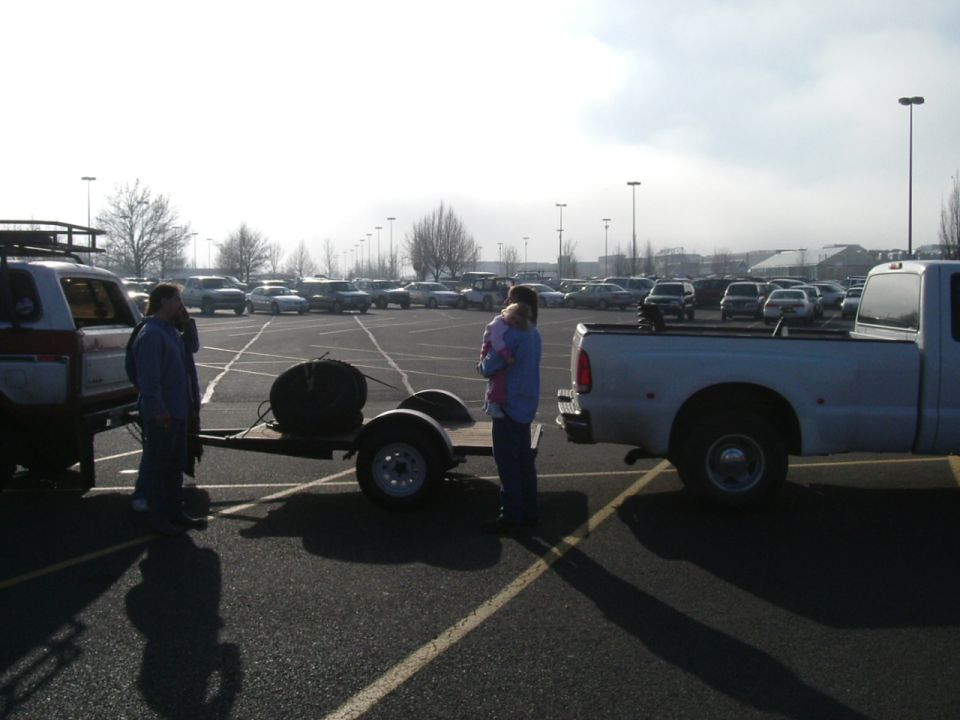 White pickup truck rear view, towing a trailer with a spare tire