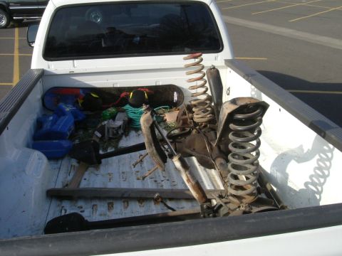 1993 Ford Bronco - Suspension components, including springs and shocks, are piled in the bed of a pickup truck.