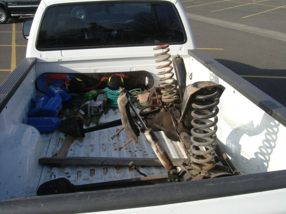 Suspension springs and shocks loaded in the bed of a white pickup truck