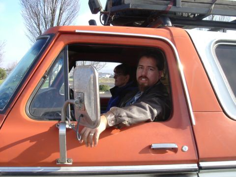 1993 Ford Bronco - Two people are inside an older model SUV, with a rack mounted on the roof.