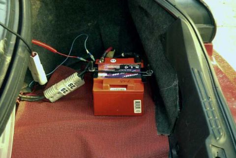 1997 Ford Taurus - Two batteries are installed in the trunk of a car, with visible wiring and connectors.