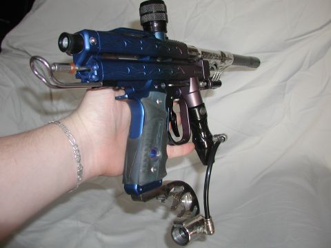 1985 Ford Bronco - A person holds a customized blue paintball gun with chrome accents against a white background.