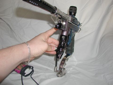 1985 Ford Bronco - A person's hand is holding a paintball marker. The marker is purple and silver with a black barrel.
