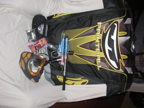 1985 Ford Bronco - A collection of paintball equipment including a mask, jersey, and marker is laid out on a white surface.