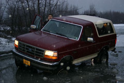 2003 Jeep TJ - A maroon Ford Bronco is partially submerged in icy water during a snowy day.
