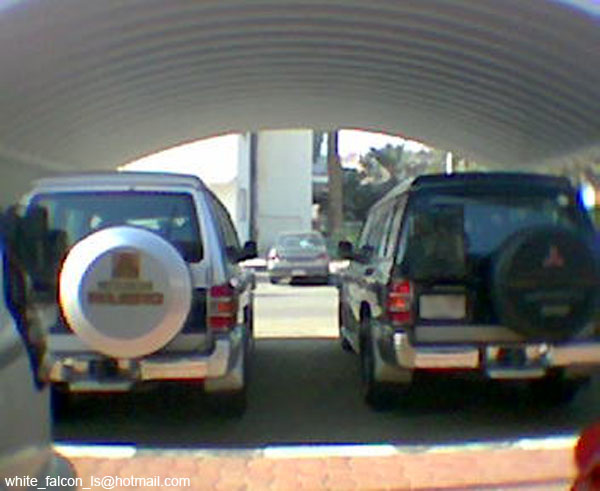 Rear of two Mitsubishi Pajero SUVs, silver and dark, with spare tire covers.