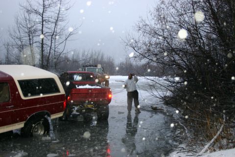 2003 Jeep TJ - Multiple vehicles are stuck on a frozen, snowy surface during a winter day.