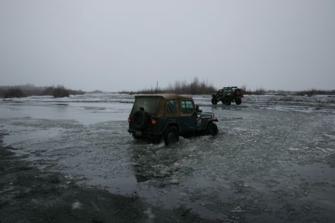2003 Jeep TJ - Two Jeeps navigate a partially frozen body of water under an overcast sky.