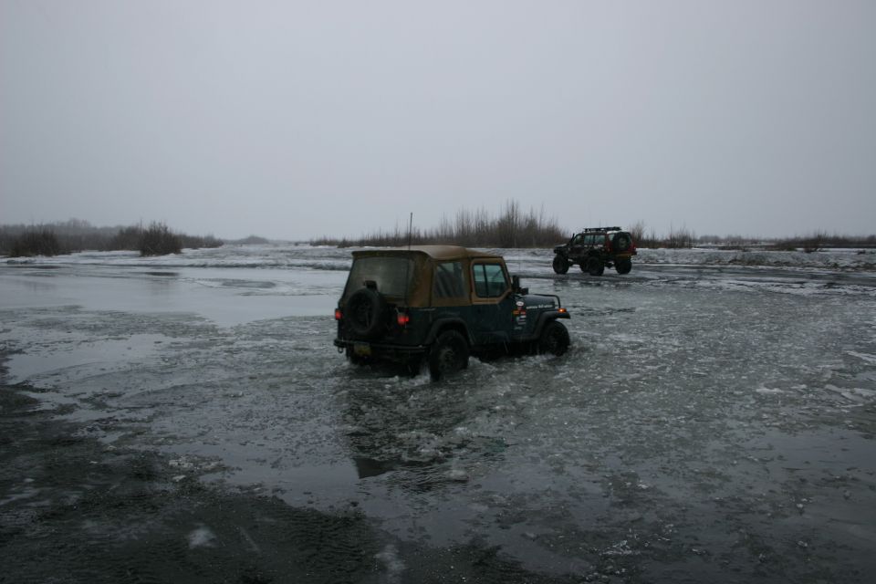 Two Jeeps driving through icy water, one in foreground, one in background