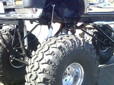 1995 Ford Bronco - Close-up view of the suspension and massive off-road tires on a heavily modified truck.