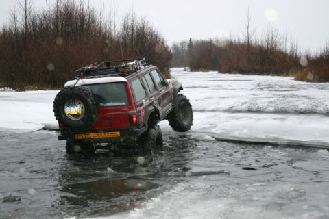 2003 Jeep TJ - Modified Jeep Cherokee XJ navigates icy terrain in a winter landscape.