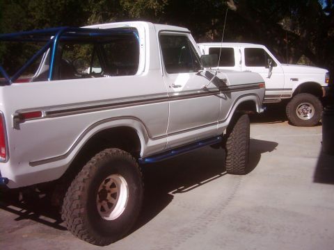 1978 Ford Bronco - This 1978 Ford Bronco features a blue roll cage and custom running boards, seen here parked alongside another vehicle.