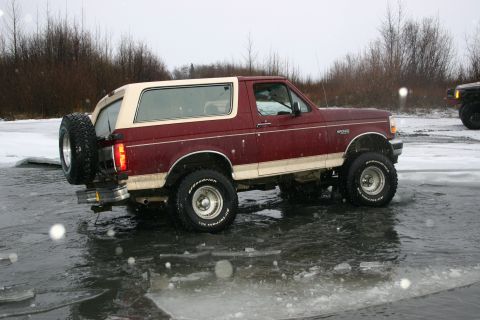 2003 Jeep TJ - Ford Bronco with lifted suspension navigates icy terrain during winter.