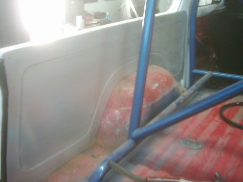 1978 Ford Bronco - The interior of a vehicle is shown, a blue roll cage and the red-painted floor of the cargo area.