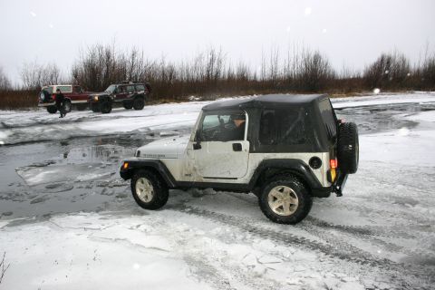 2003 Jeep TJ - White 2003 Jeep TJ navigates icy terrain with other vehicles in the background.
