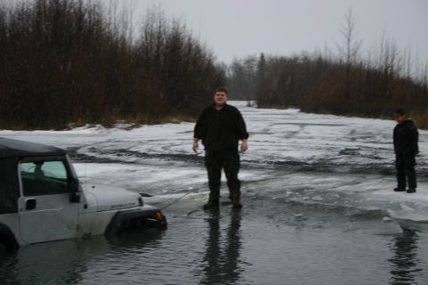 2003 Jeep TJ - Jeep TJ stuck in icy water, with two people standing nearby in winter conditions.