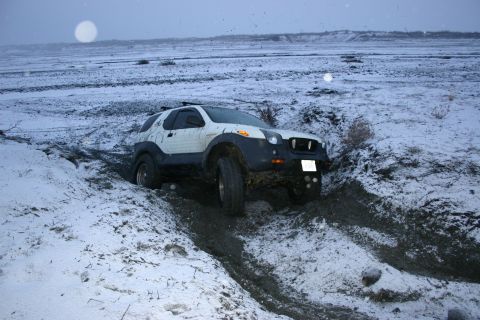 2003 Jeep TJ - An SUV navigates a challenging muddy and snowy terrain.
