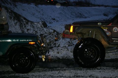 2003 Jeep TJ - Two off-road vehicles are parked close together in a snowy, outdoor environment during twilight.
