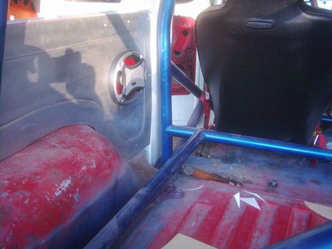 1978 Ford Bronco - The interior of a 1978 Ford Bronco shows a blue roll cage and a black racing seat.