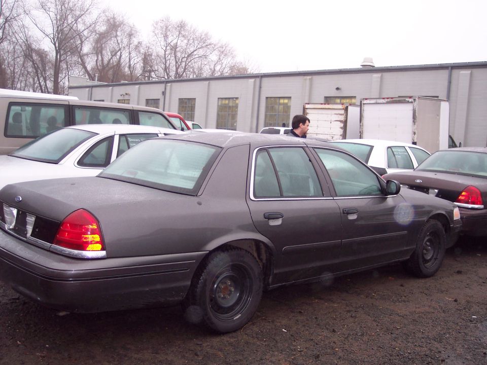 Dark gray 1992 Ford Crown Victoria sedan, side view, parked on dirt lot