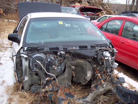 1991 Ford LTD Crown Victoria - Front view of a white car in a junkyard, showing its dismantled engine bay and windshield markings.