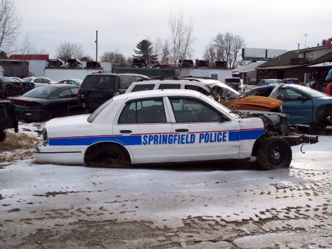 1991 Ford LTD Crown Victoria - Junkyard scene with a stripped 1991 Ford Crown Victoria LTD police car and other vehicles.