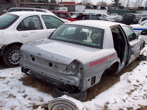 1991 Ford LTD Crown Victoria - This damaged Ford Crown Victoria, likely from the early 2000s, has 'Emergency 911' and 'POLICE' markings.