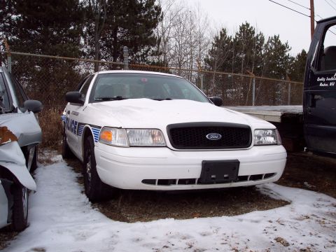 1991 Ford LTD Crown Victoria - White police car parked in snow, with another vehicle to its left and a truck to its right.